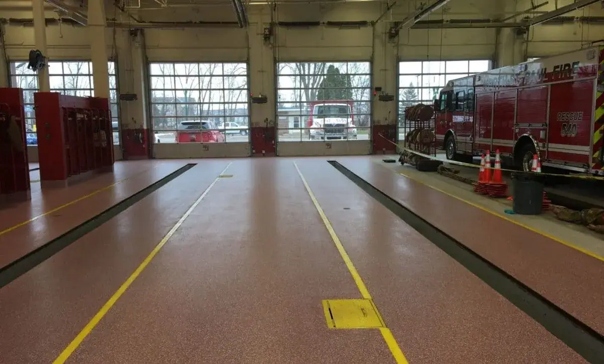 Fire station apparatus bay with a red coated floor and yellow striping
