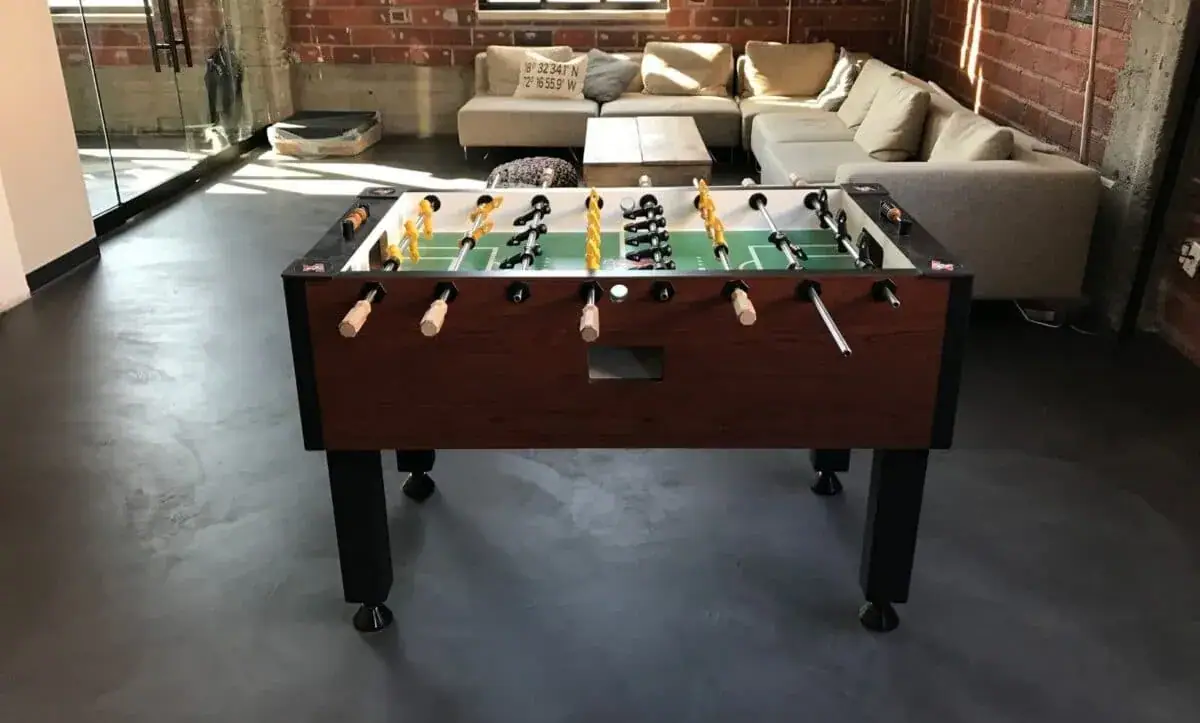 Coated basement rec room floor with a foosball table and sofa